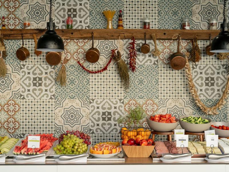 Buffet mit Obst, Gemüse und Gewürzen vor einer bunten Tapetenwand im rustikalen Stil.