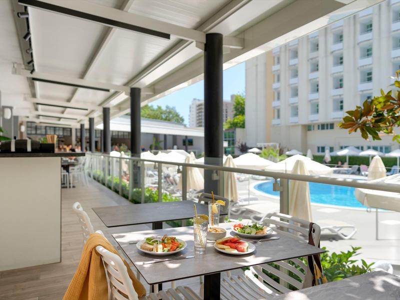 Moderner Außenbereich eines Hotels mit gedeckten Tischen und Blick auf den Pool