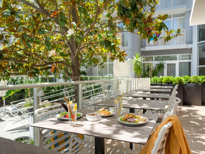 Heller Außenbereich eines Hotels mit gedecktem Tisch und moderner Gartenmöbel.