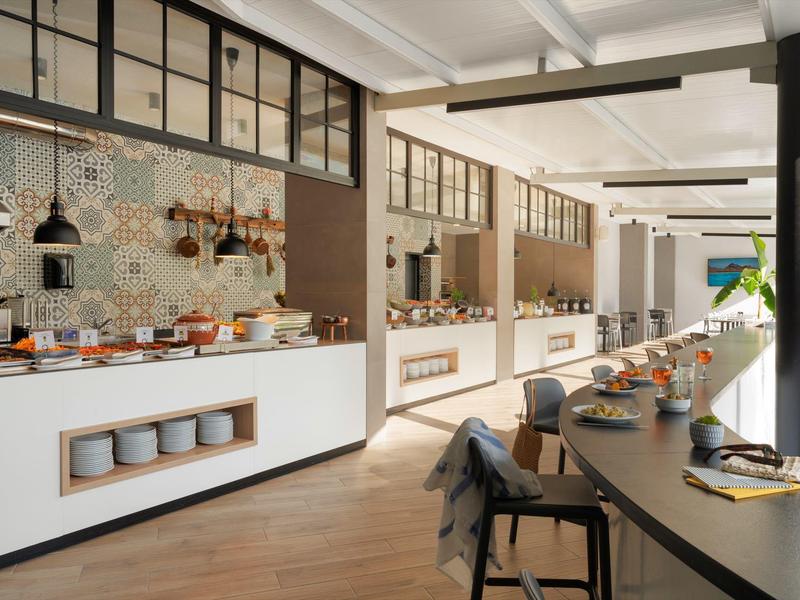 Modernes Buffet mit Geschirr und Frühstücksoptionen in einem hellen Hotelrestaurant.