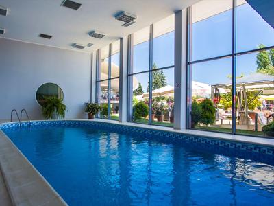 Piscina coperta con grandi finestre che si affacciano su una terrazza e cielo limpido