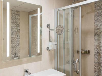 Moderner Badezimmerbereich mit Glas-Dusche, großem Spiegel und weißem Waschbecken.