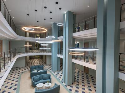 Modernes Hotel-Lobby-Interieur mit runden Sitzbereichen und schwebenden Ringlampen.