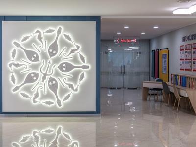 Flur mit moderner Beleuchtung, glänzendem Boden und Sitzbereich mit Tischen und Stühlen.