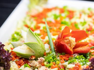 Bunte Gemüseplatte mit roten Paprika, grünen Erbsen, weißen Stücken und lila Blattsalat dekoriert.