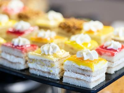 Verschiedene bunte kleine Schichtdesserts mit Sahnetopping auf Tablett, ideal für Hotelbuffet.