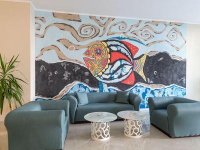 Moderner Hotellounge-Bereich mit blaugrünen Sitzmöbeln und einer farbenfrohen Wandmalerei.