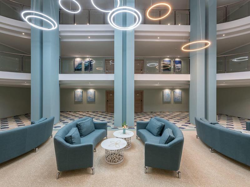 Modernes Hotellobby mit blauen Sitzgruppen und runden Hängelichtern.