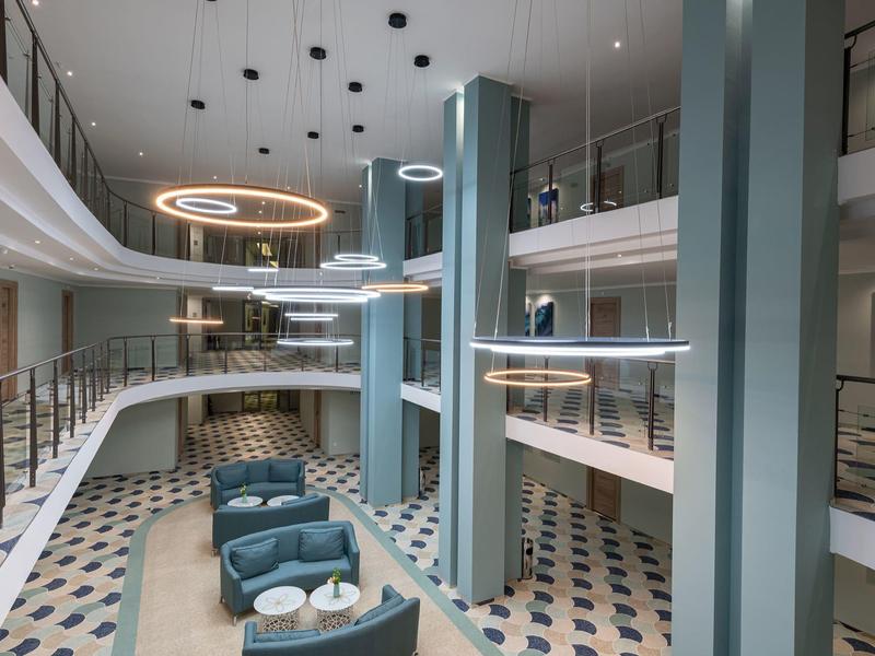 Modernes Hotel-Lobby-Interieur mit runden Sitzbereichen und schwebenden Ringlampen.