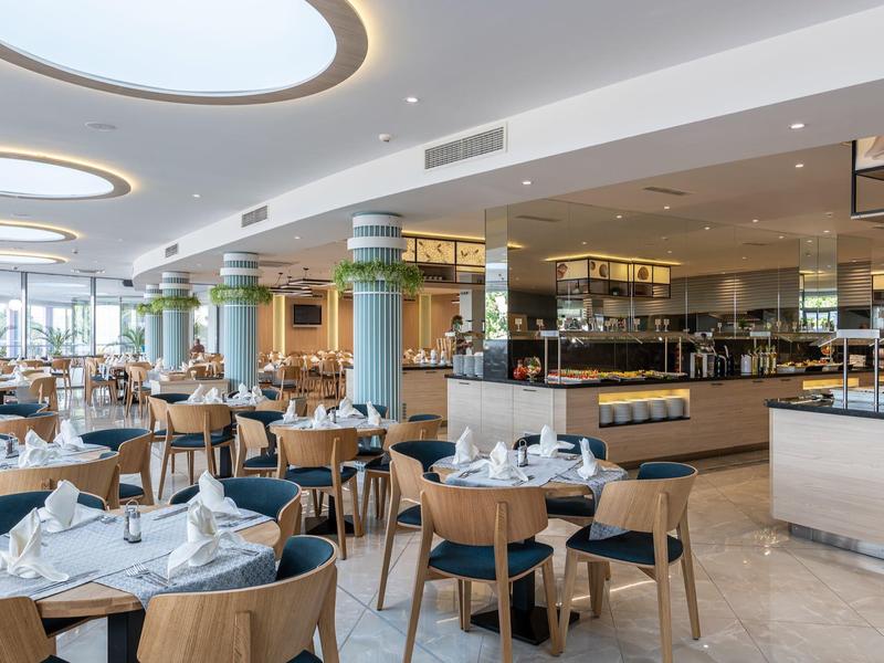 Geräumiges Restaurant mit modernen Holztischen, bequemen Stühlen und großem Fenster für Tageslicht.