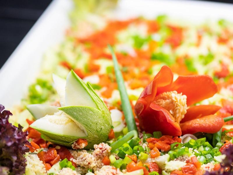 Bunte Gemüseplatte mit roten Paprika, grünen Erbsen, weißen Stücken und lila Blattsalat dekoriert.