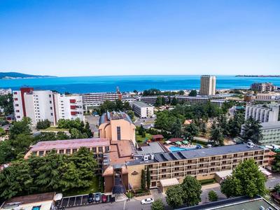 Blick auf Stadt mit Hotels, viel Grünfläche und blauem Meer am Horizont bei sonnigem Wetter.