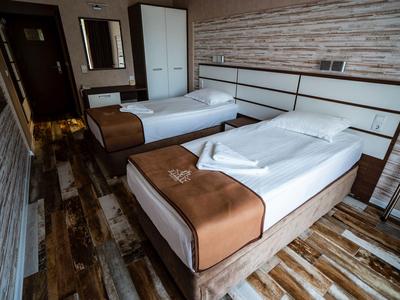 Modernes Hotelzimmer mit zwei Einzelbetten, Holzboden und Holzwandverkleidung.
