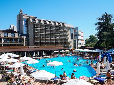 Belebter Hotelpool mit Sonnenschirmen und Liegestühlen an einem sonnigen Tag.