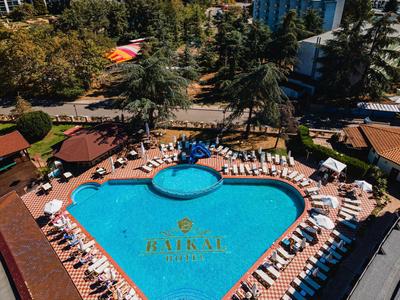 Herzförmiger Pool mit Liegestühlen in einem Hotelresort nahe Strand und Stadt.