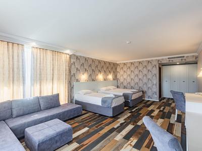 Modern eingerichtetes Hotelzimmer mit zwei Betten, Sofa und schickem Holzfußboden.