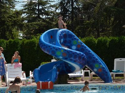Blauer Wasserrutschen-Turm an einem Hotelpool mit Personen im Wasser und am Beckenrand.