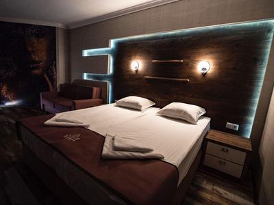 Modernes Hotelzimmer mit großem Doppelbett, indirekter Beleuchtung und dunkelbraunen Akzenten.