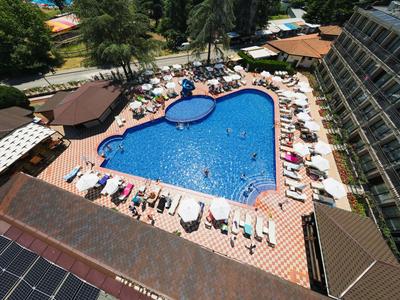 Außenpool eines Hotels mit Liegestühlen, Sonnenschirmen und angrenzender Gartenanlage.
