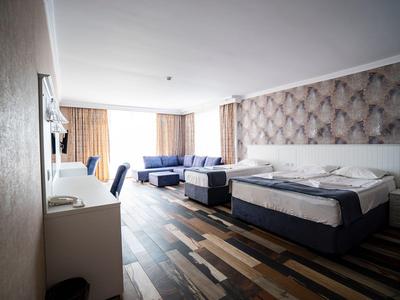 Modern eingerichtetes Hotelzimmer mit zwei Betten, Sofa und Holzboden.