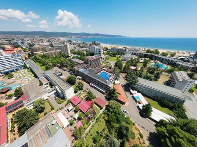 Blick auf eine Küstenstadt mit Hotels, Straßen und dem Meer im Hintergrund unter blauem Himmel.