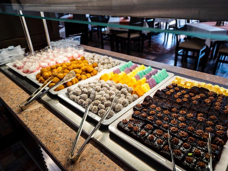 Buffet met diverse lekkernijen en gebak op witte schalen in een hotelrestaurant.