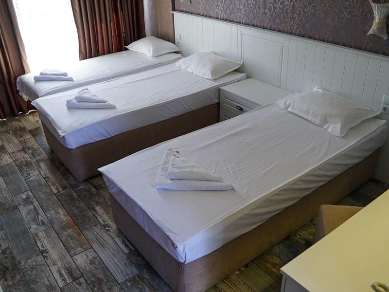 Een hotelkamer met twee eenpersoonsbedden, schone witte lakens en houten vloeren.