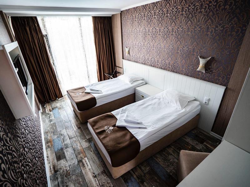 Hotelkamer met twee eenpersoonsbedden, grote ramen en modern bruin-wit interieur.