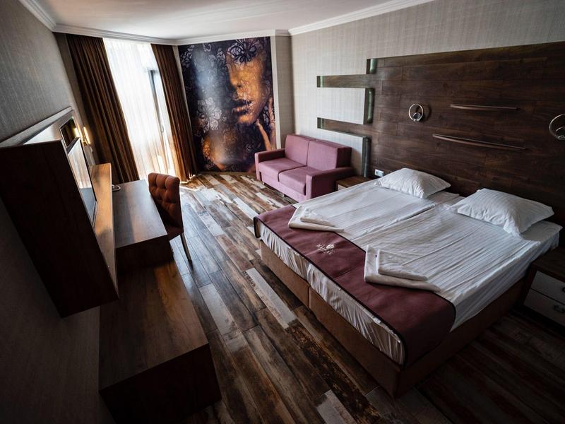 Modern ingerichte hotelkamer met tweepersoonsbed, bank en grote ramen.