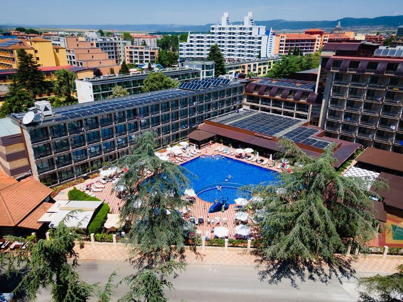 Hotel met groot buitenzwembad en ligstoelen omgeven door stedelijke gebouwen.