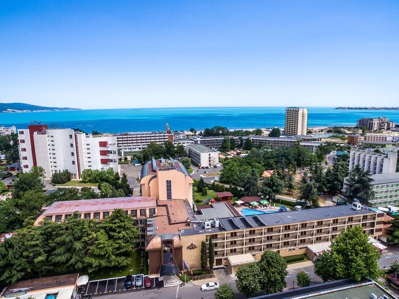 Stedelijk kustlandschap met gebouwen en brede zee op de achtergrond bij heldere lucht.