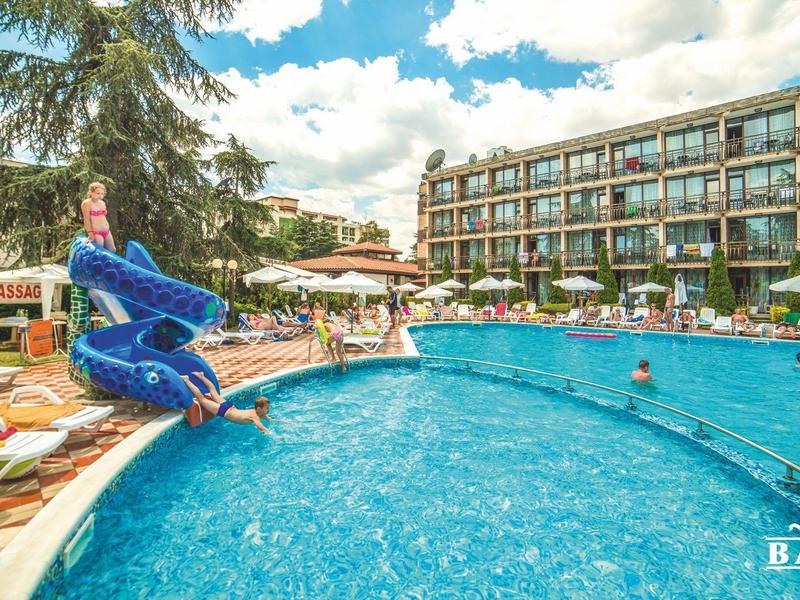 Groot buitenzwembad met glijbaan en parasols voor een meerlaagse hotel.