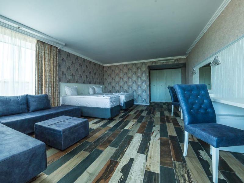 Ruime hotelkamer met blauwe stoelen, bank en flatscreen-tv.