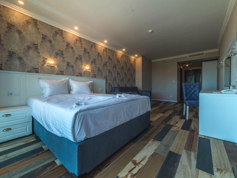 Modern ingerichte hotelkamer met groot bed en zithoek.