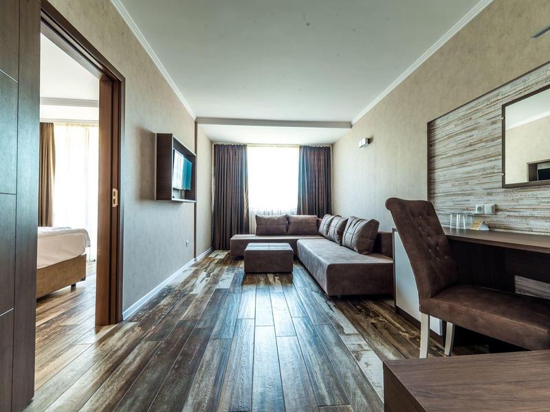 Moderne hotelsuite met woonkamer, bureau en aangrenzende slaapkamer.