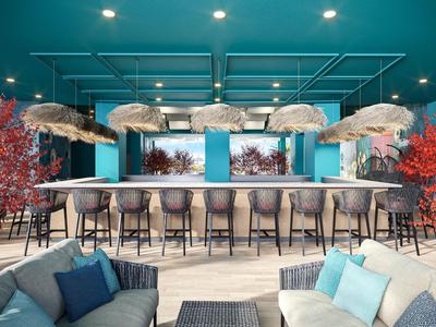 Nowoczesny bar hotelowy z niebieskimi ścianami, miejscami do siedzenia i efektownym oświetleniem sufitowym.