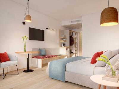 Habitación de hotel moderna con cama grande, área de descanso, detalles cálidos de madera y decoración minimalista.