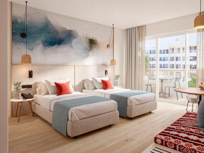 Elegante habitación de hotel con dos camas individuales, arte moderno y balcón con vistas a edificios vecinos.