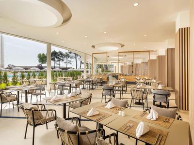 Comedor moderno y luminoso con mesas preparadas y grandes ventanas con vistas al exterior.