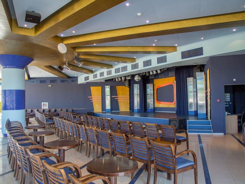 Gran sala de conferencias con filas de sillas y escenario al fondo.