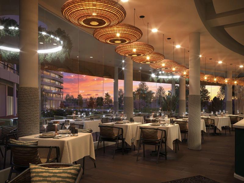 Restaurante elegante con mesas preparadas y luces cálidas en el techo al atardecer.