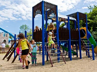 Kinderen spelen op een blauw en bruin klimrek op een buiten speelplaats.