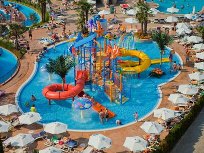 Hotel met zwembad, parasols en tuin direct aan het strand bij zonnig weer.