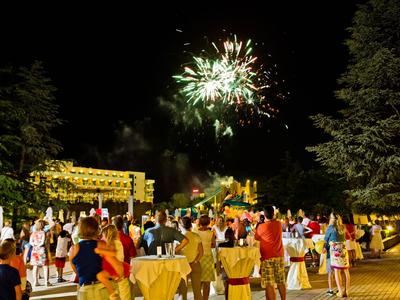 Persone che festeggiano all'aperto di notte con fuochi d'artificio e area evento decorata.