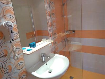 Moderne badkamer met witte wastafel, spiegel en oranje strepen op de muur.