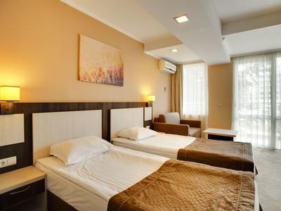 Modern hotelkamer met twee eenpersoonsbedden, warme kleuren en groot raam.