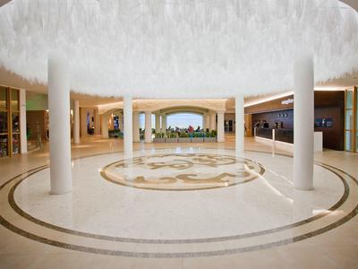 Ruime hotellobby met ronde lichte plafond en zuilen, met uitzicht op tuin op de achtergrond