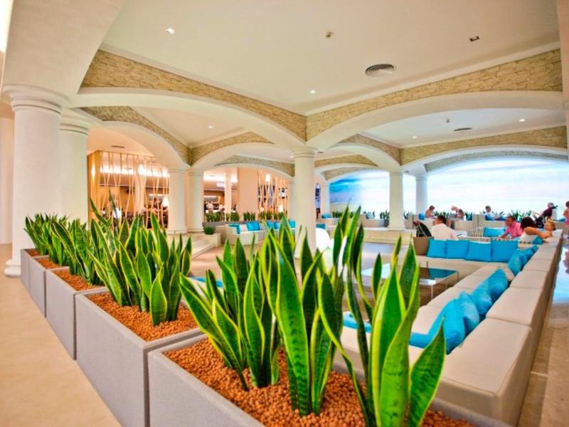 Moderne, lichte hotelinterieur met groene planten en comfortabele zitplaatsen.