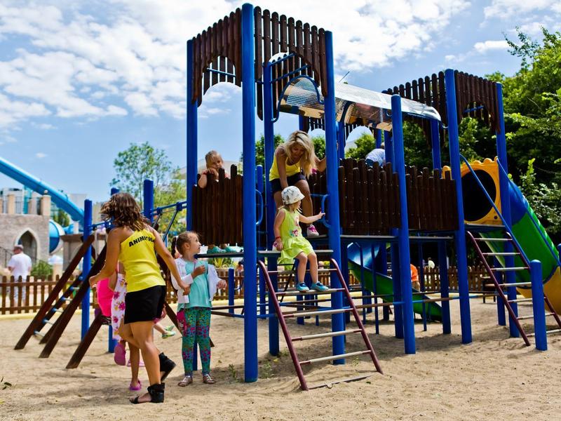 Kinderen spelen op een blauw en bruin klimrek op een buiten speelplaats.