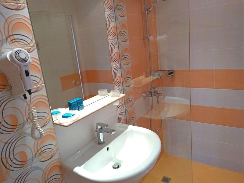 Moderne badkamer met witte wastafel, spiegel en oranje strepen op de muur.